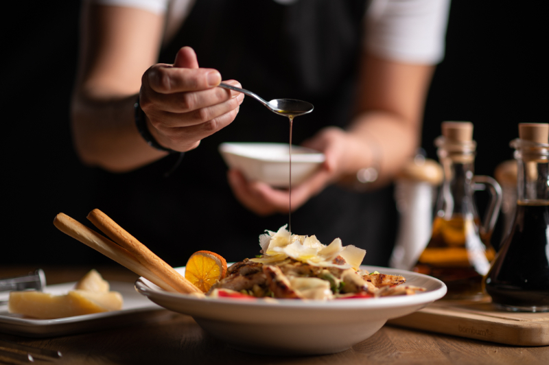 A female chef pouring sauce on salad