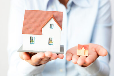 man holding miniature house (big and small)